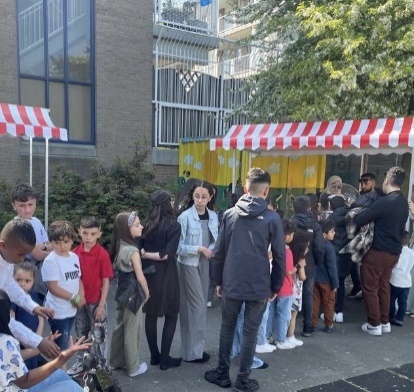 Bezoekers bij de kraampjes met rood-witte luifels tijdens het straatfeest op het Ruth Firstplein